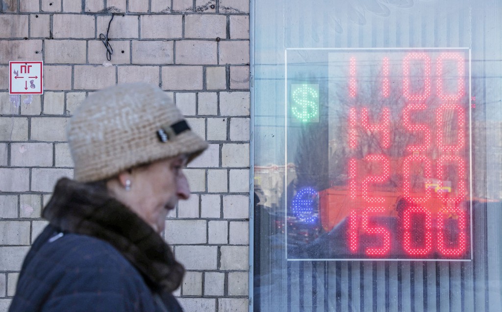 Жена пролази испред табле на којој су приказани курсеви евра и америчког долара у односу на руску рубљу.