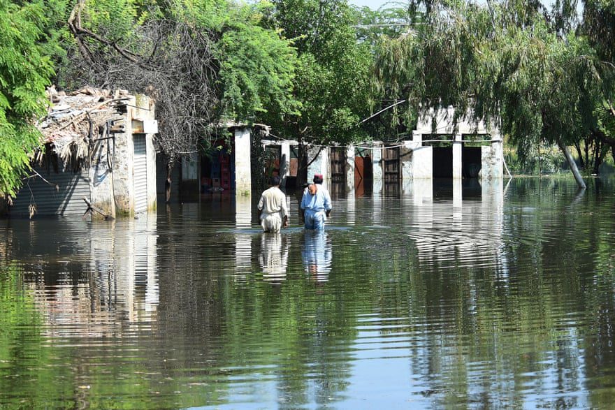 Становници газе у поплавним водама у близини својих домова након обилних монсунских киша.