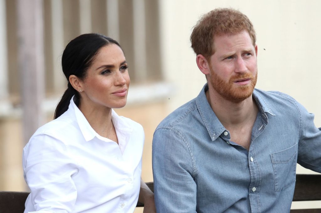 Meghan Markle and Prince Harry sit side by side.