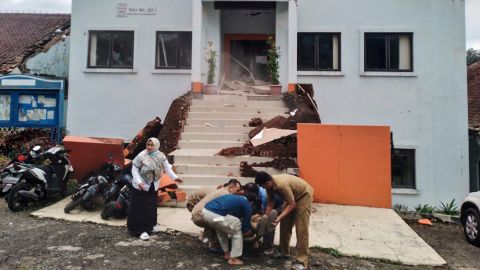 Општински службеници у Циањуру евакуишу повређеног колегу након земљотреса.