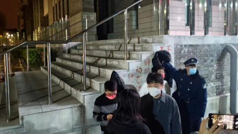 Чувар покушава да покрије транспарент протеста против Зеро Цовида у кампусу Пекиншког универзитета у Пекингу.